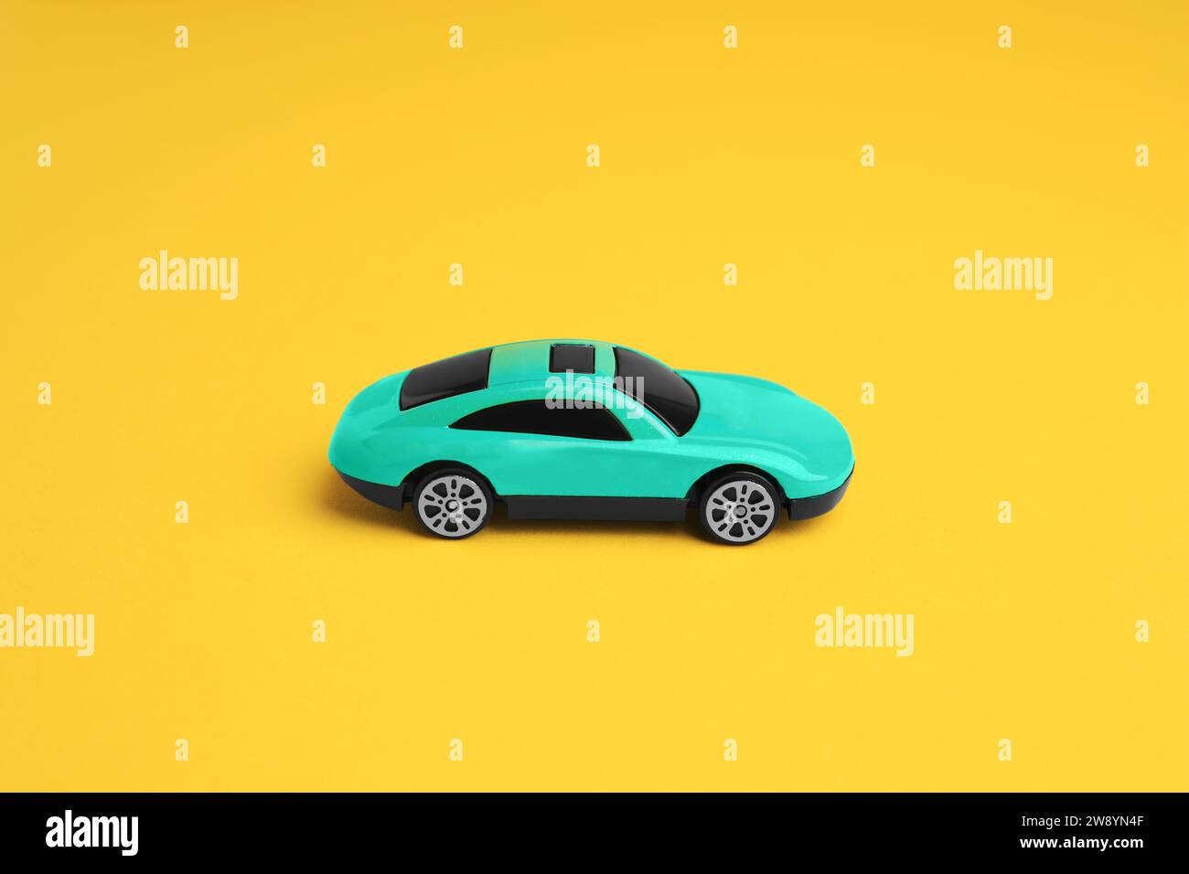 One turquoise car on yellow background. Children`s toy Stock Photo